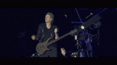 A Man Is Playing A Guitar On A Stage GIF
