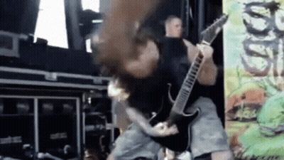 A Man Is Playing A Guitar On A Stage While A Woman Holds His Head . GIF