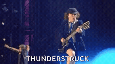 A Man Is Playing A Guitar On A Stage With The Words `` Thunderstruck '' Behind Him . GIF