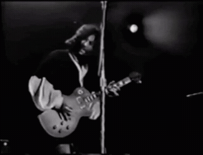 A Man Is Playing A Guitar On Stage In A Black And White Photo . GIF