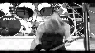 A Man Is Playing A Guitar On Stage In Front Of A Drum Set . GIF
