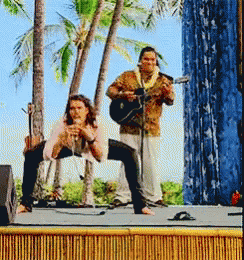 A Man Is Playing A Guitar While A Woman Sings On Stage GIF