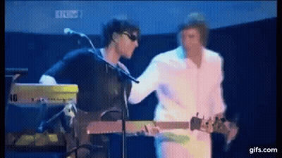 A Man Is Playing A Guitar While Another Man Is Playing A Keyboard On Stage . GIF
