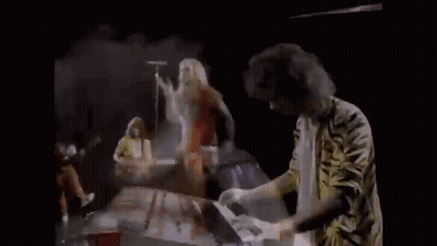 A Man Is Playing A Piano And Holding A Piece Of Paper In His Hands . GIF