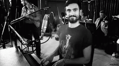 A Man Is Playing A Piano In A Black And White Photo While A Band Plays In The Background . GIF