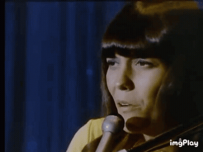 A Man Is Playing A Piano In A Dark Room While Another Man Is Playing Drums In The Background . GIF