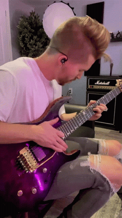 A Man Is Playing A Purple Guitar In Front Of A Marshall Amp GIF