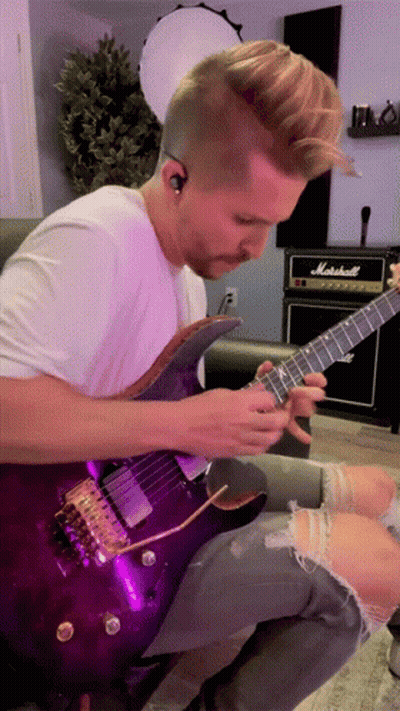 A Man Is Playing A Purple Guitar In Front Of A Marshall Amp GIF