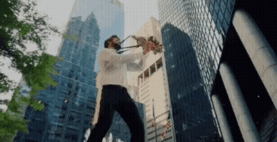A Man Is Playing A Saxophone In Front Of A City Skyline GIF