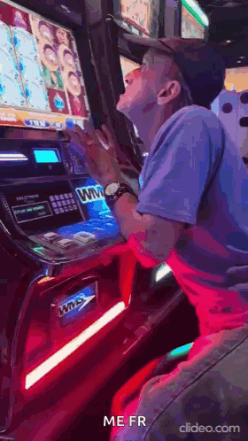 A Man Is Playing A Slot Machine In A Casino And Making A Funny Face . GIF