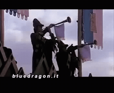 A Man Is Playing A Trumpet In Front Of A Crowd Of People In A Castle . GIF