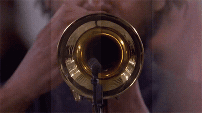 A Man Is Playing A Trumpet With A Microphone Attached To It GIF