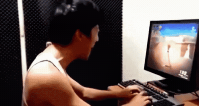 A Man Is Playing A Video Game On A Computer While Sitting At A Desk . GIF