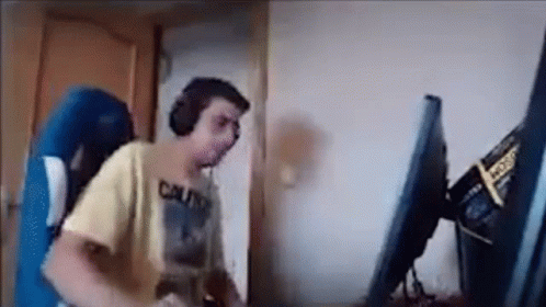 A Man Is Playing A Video Game On A Computer While Wearing Headphones . GIF