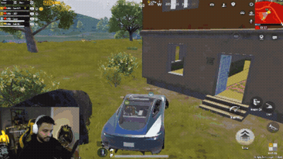 A Man Is Playing A Video Game With A Car In The Background GIF