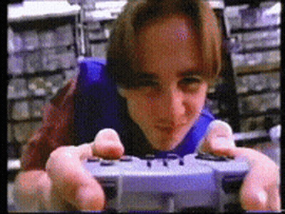 A Man Is Playing A Video Game With A Controller That Says Playstation GIF