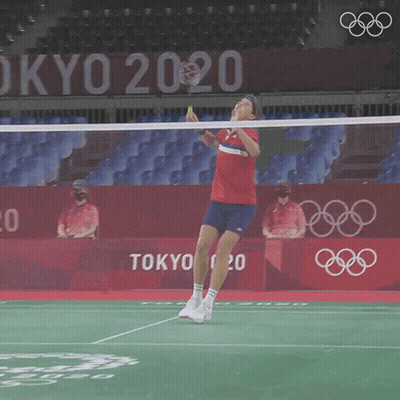 A Man Is Playing Badminton In Front Of A Tokyo 2020 Sign GIF
