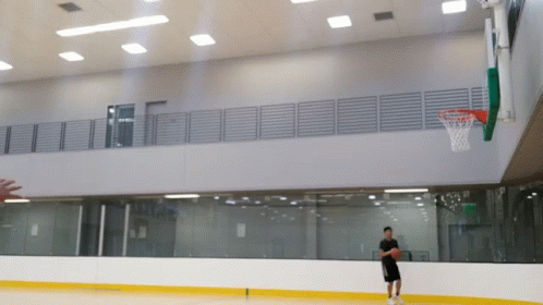 a man is playing basketball in a gym with a hoop in the background