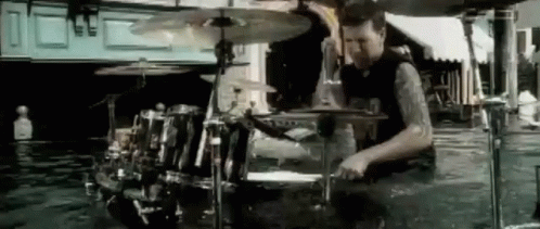A Man Is Playing Drums In A Room Filled With Water . GIF