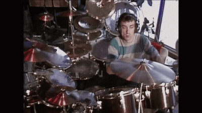 A Man Is Playing Drums In A Room With A Lot Of Drums And Cymbals . GIF