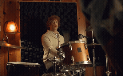 A Man Is Playing Drums In A Room With A Microphone GIF