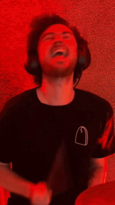 A Man Is Playing Drums In Front Of A Neon Sign That Says ' Music ' GIF