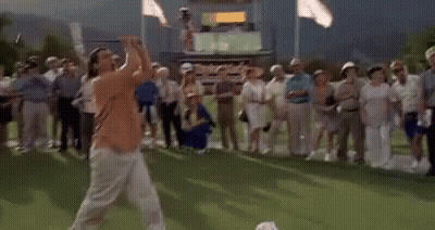 A Man Is Playing Golf On A Green While A Crowd Watches . GIF