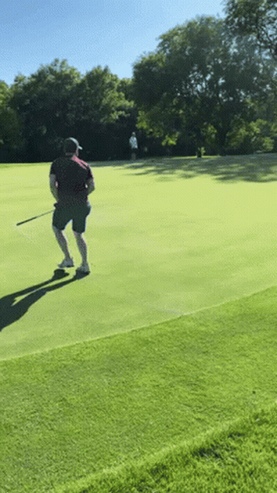 A Man Is Playing Golf On A Lush Green Course GIF