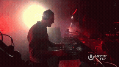 A Man Is Playing Music In A Dark Room With A Sign That Says Umf Tu GIF