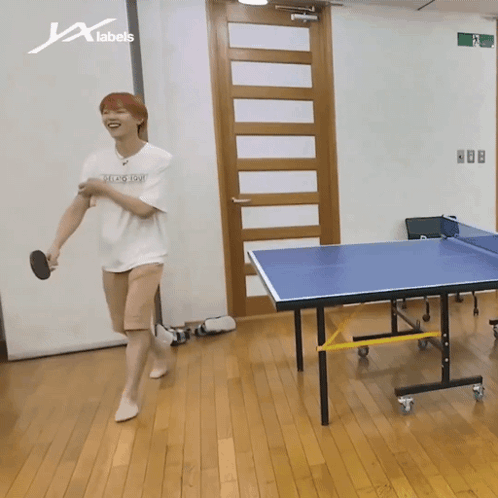A Man Is Playing Ping Pong In A Room With A Sign That Says X Labels GIF