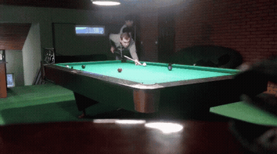 A Man Is Playing Pool In A Room With A Brick Wall GIF