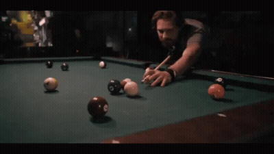 A Man Is Playing Pool With A Cue And Balls That Have The Number 8 On Them GIF