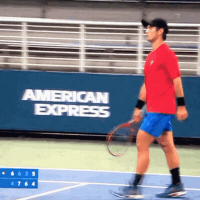 A Man Is Playing Tennis In Front Of A Banner That Says American Express GIF