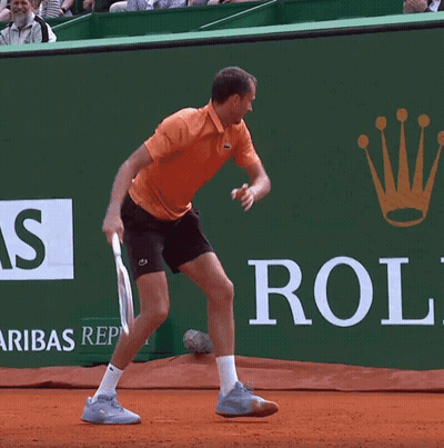 A Man Is Playing Tennis In Front Of A Rolex Ad GIF