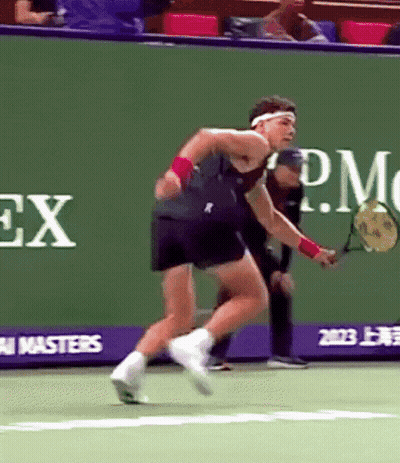 A Man Is Playing Tennis In Front Of A Rolex Advertisement GIF