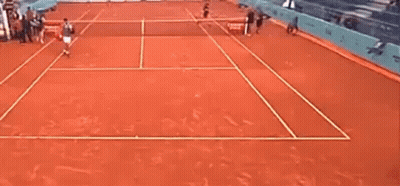 A Man Is Playing Tennis On A Clay Court . GIF