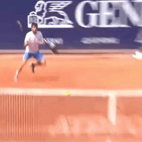 A Man Is Playing Tennis On A Court In Front Of A Sign That Says Gen GIF