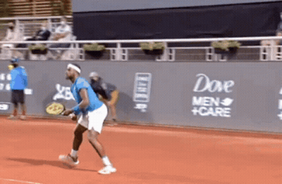 A Man Is Playing Tennis On A Court With A Dove Men 'S Care Advertisement On The Wall Behind Him GIF