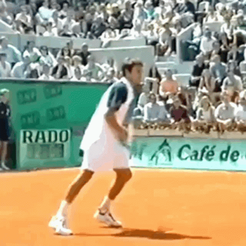 A Man Is Playing Tennis On A Court With A Rado Sign In The Background GIF