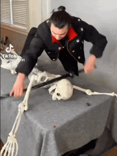 A Man Is Playing With A Skeleton On A Table With Tik Tok Written On The Bottom Right GIF