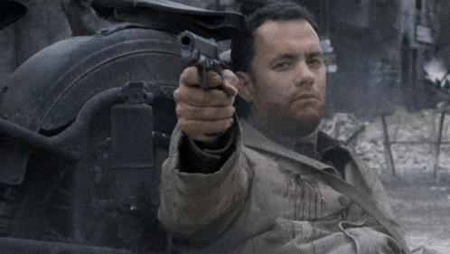 A Man Is Pointing A Gun At Something In The Distance GIF