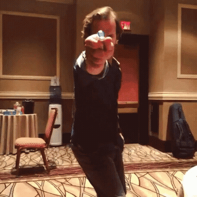 A Man Is Pointing At The Camera With A Blue Object In His Hand GIF