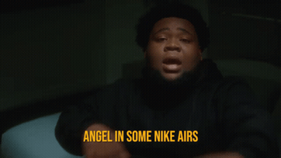 A Man Is Pointing At The Camera With The Words Angel In Some Nike Airs Behind Him GIF