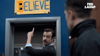 A Man Is Pointing To A Sign That Says Believe GIF