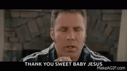 A Man Is Praying With His Eyes Closed In Front Of A Fireplace While Wearing A Black Jacket . GIF