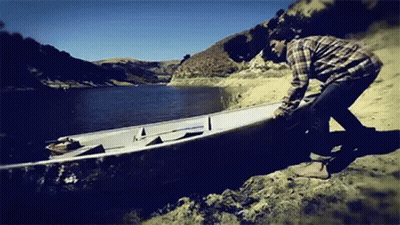 A Man Is Pushing A Boat Into The Water GIF