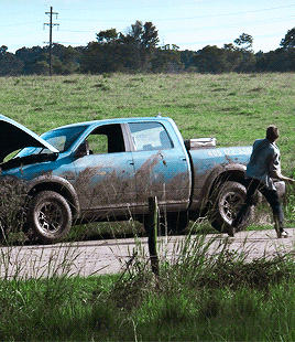 A Man Is Pushing A Muddy Truck That Has A Sticker On The Back That Says ' Emergency Assistance ' GIF