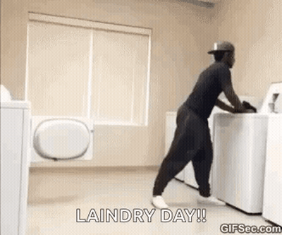 A Man Is Pushing A Washing Machine In A Laundry Room . GIF