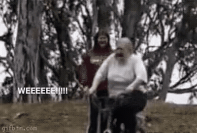 A Man Is Pushing An Elderly Woman On A Bicycle In A Forest . GIF