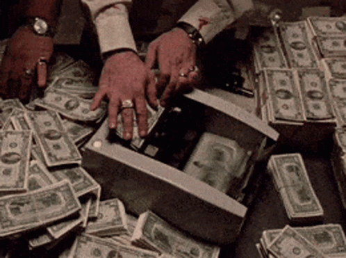 A Man Is Putting A Gun In A Box Surrounded By Stacks Of Money GIF
